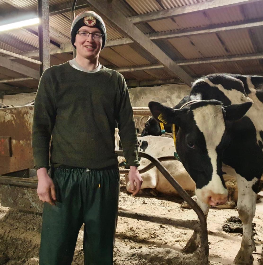 Gearoid Murphy standing with cows in barn